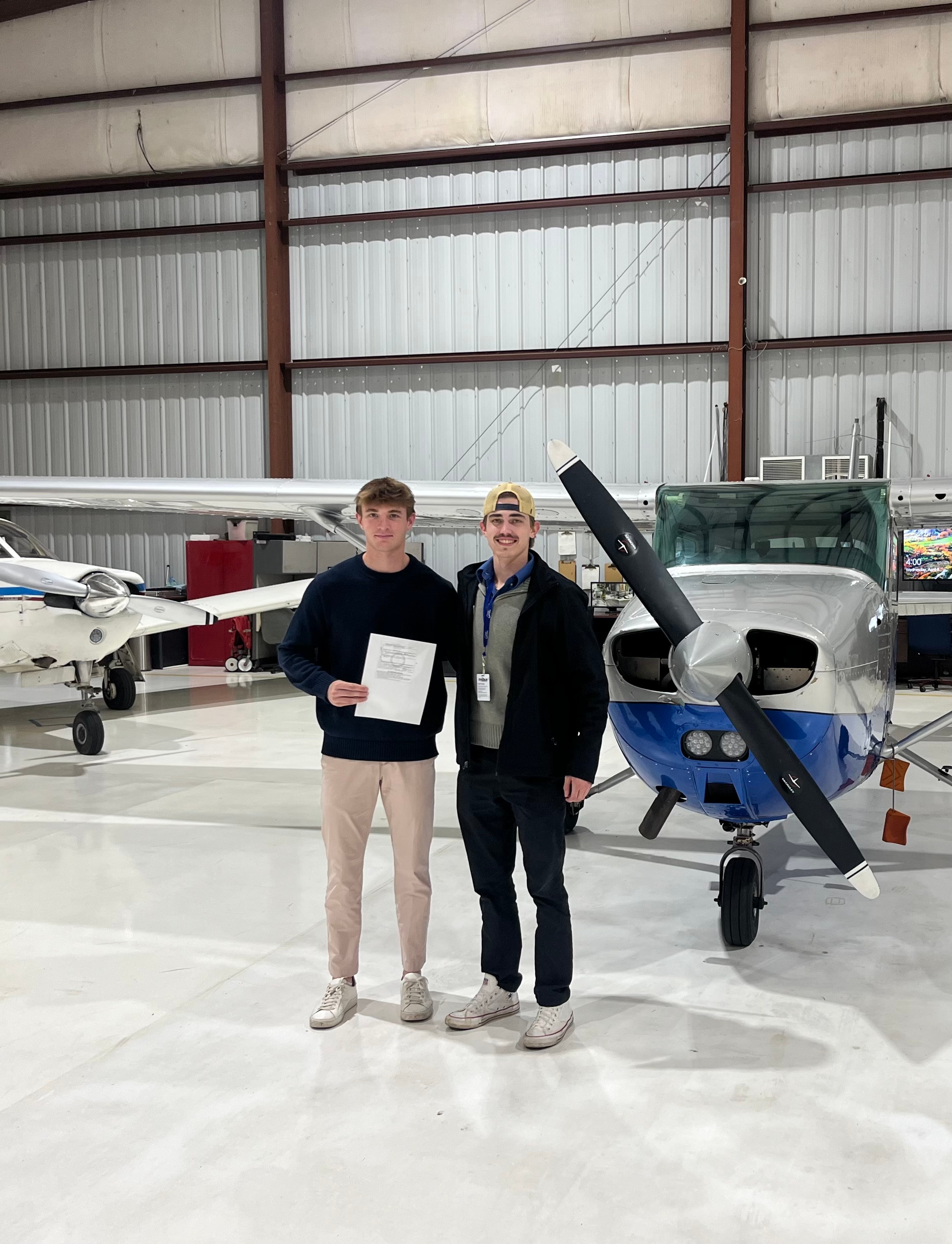 Mark Rolfes with a student pilot in the hangar beside a training aircraft.