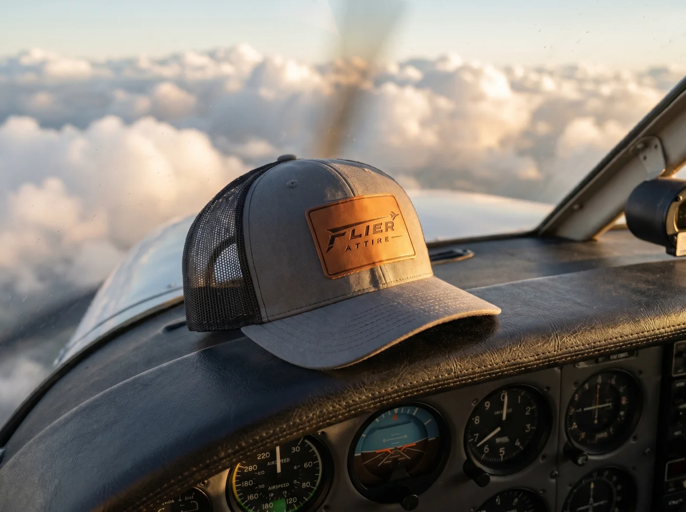 The Signature trucker hat resting on a small aircraft cockpit dash mid flight